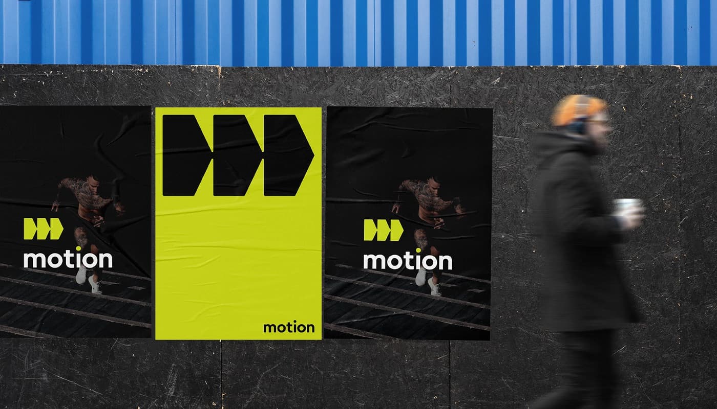 Plakate der Marke motion an einer Bauwand, eine Person geht vorbei
